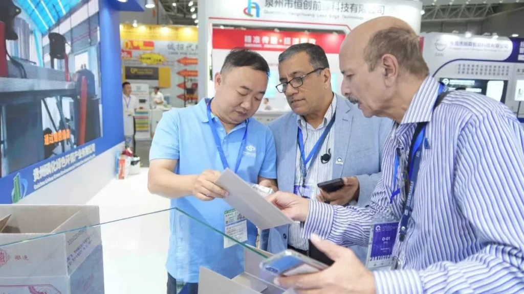 About Us Xianghui Pack team discussing a corrugated plastic packaging sample with buyers at a trade show