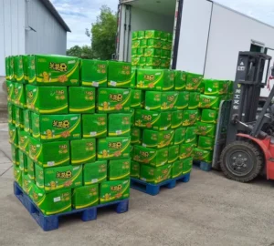 Pallets of printed packaging boxes beside a forklift and delivery truck