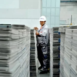 Factory worker checking stacked corrugated plastic goods before dispatch